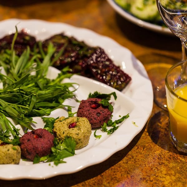 Georgian pkhali appetizers, green and red, garnished with herbs on a white plate.